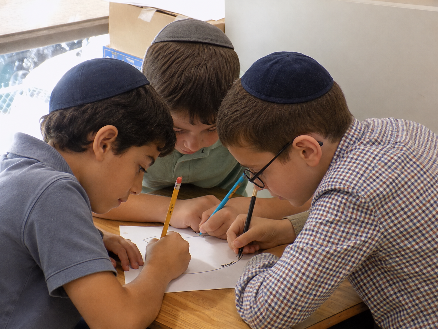 Three students working together over printed curriculum materials
